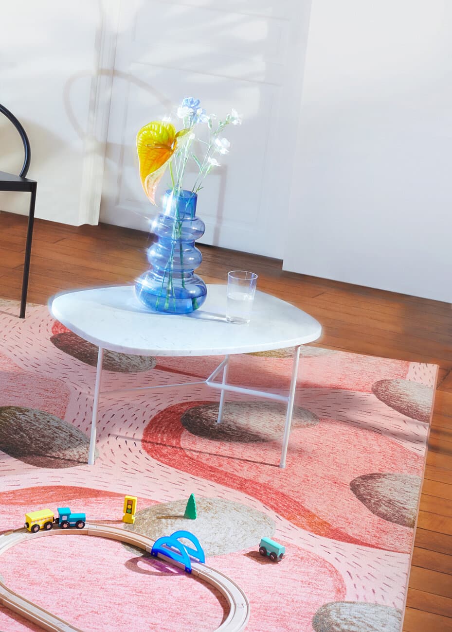 A second rug from Guillaume Delvigne’s 2019 anniversary collection, shown beneath a round table with a wooden toy train