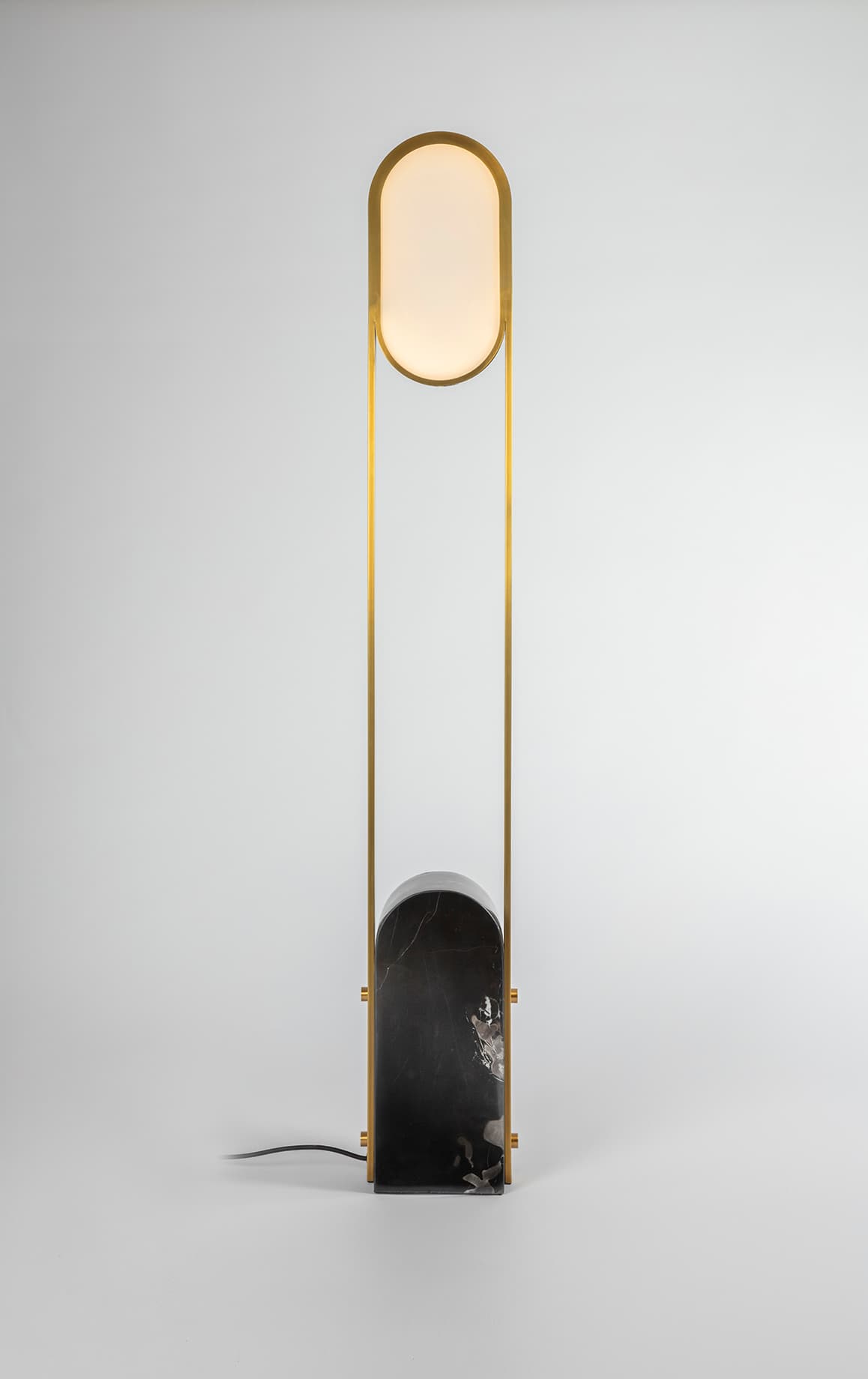 Pill floor lamp by Square In Circle, with an oval frosted diffuser, brass frame and dark marble base