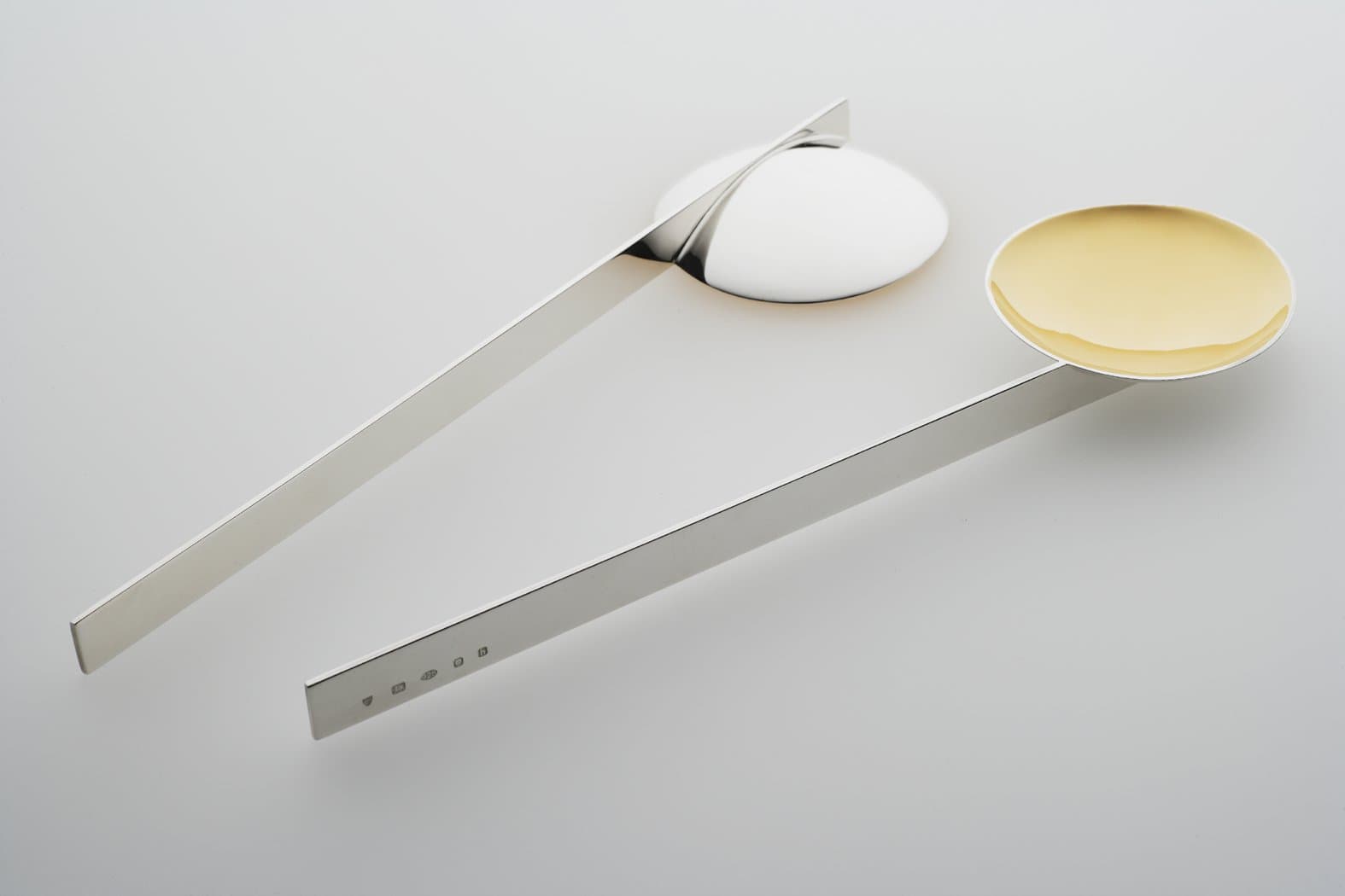 Jacqueline Scholes: a pair of condiment spoons, one with a gold-coloured bowl.