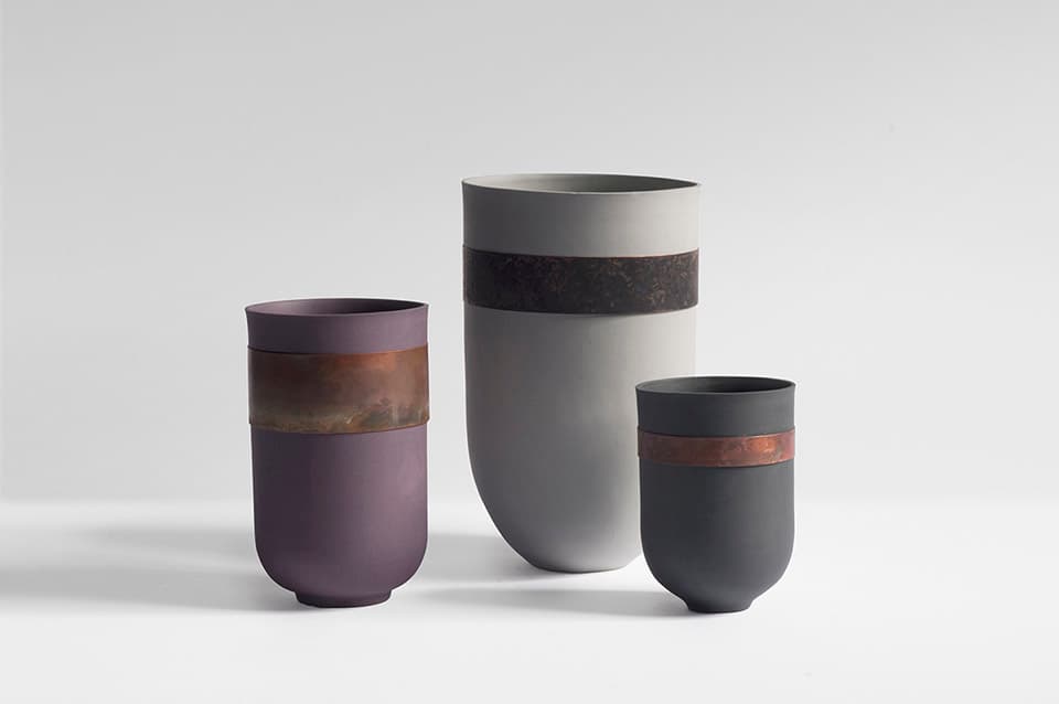 Three vases from Marie Liebhardt’s Flaws metal collection, combining coloured porcelain with aged copper and brass
