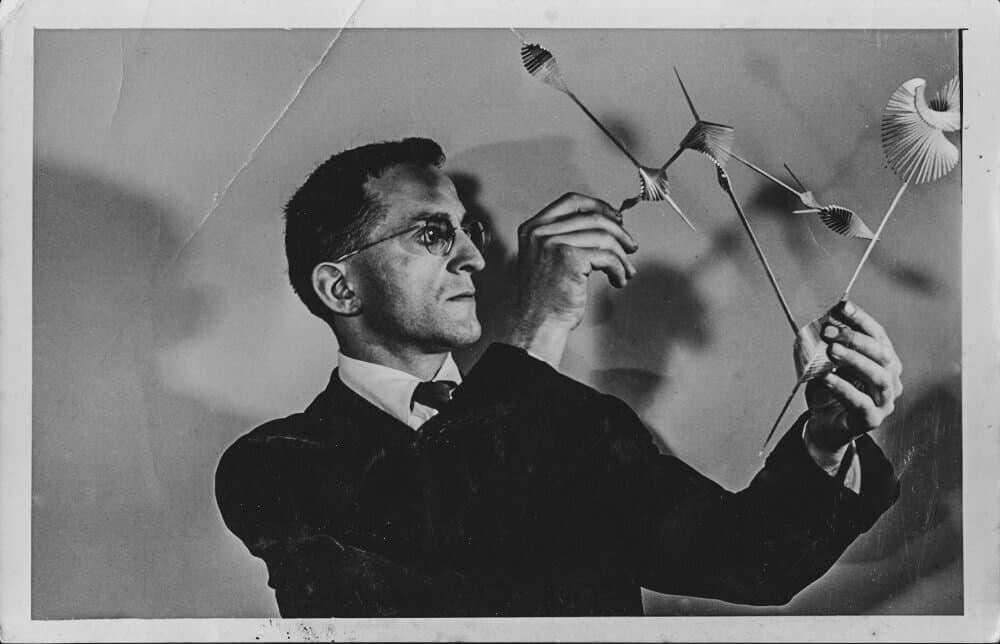 Serge Mouille handling small sculptural forms, in an archival photograph reproduced by his official history site.