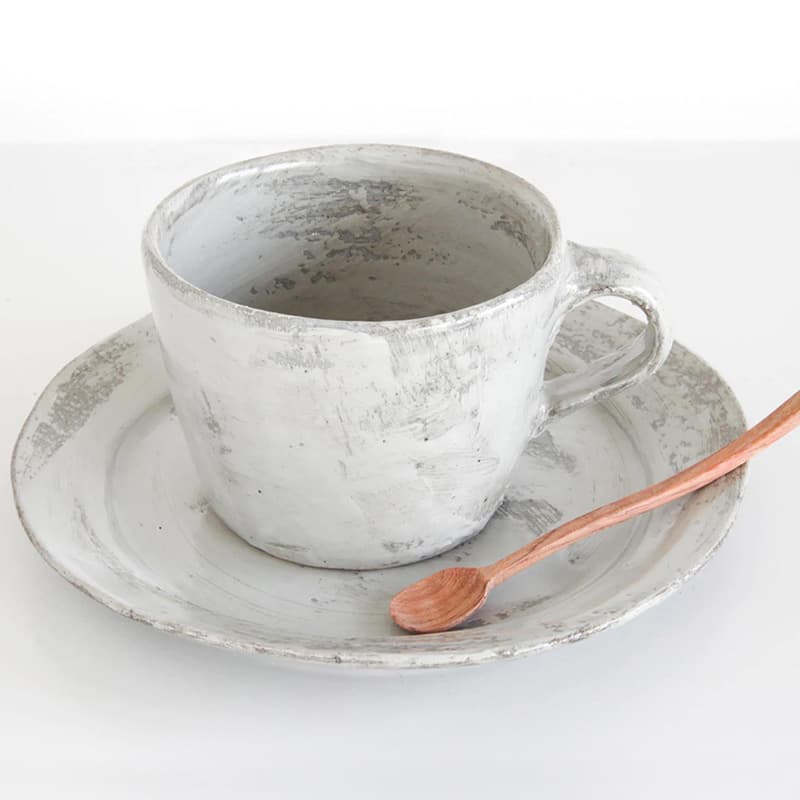 Rustic pale ceramic cup and saucer by Katsufumi Baba, with a small copper-coloured spoon.