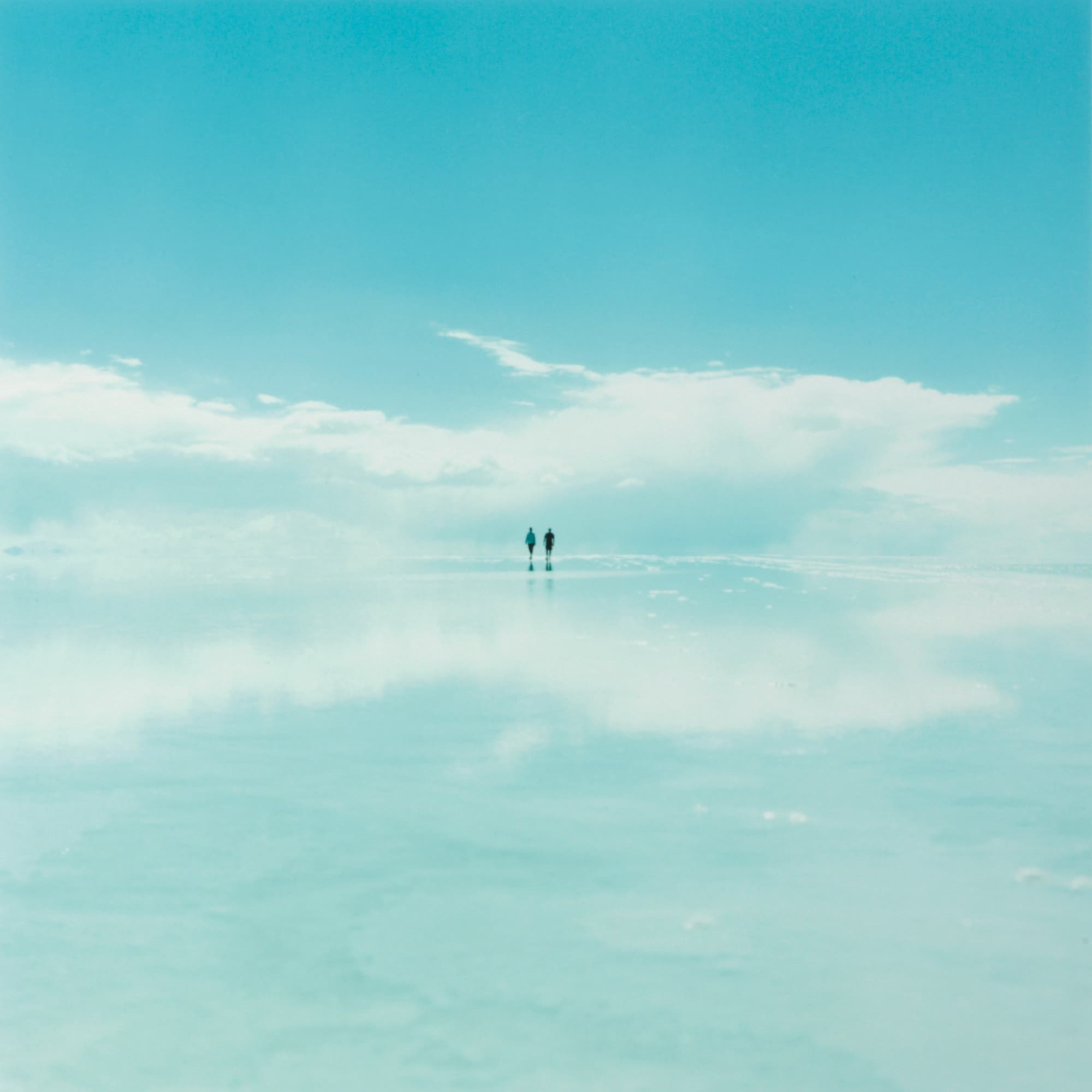 On Her Skin (2006) — two distant figures amid blue sky and reflected clouds