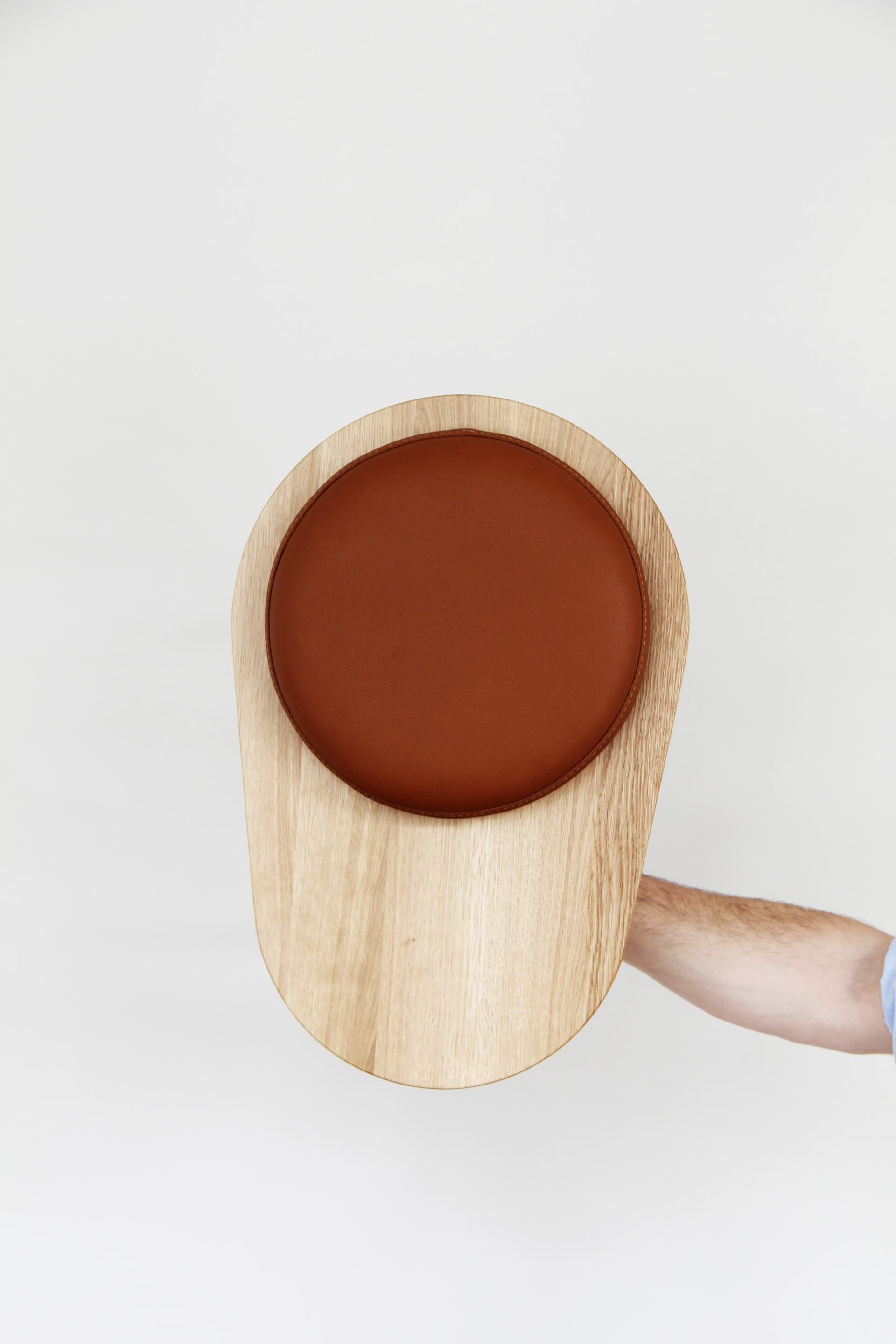 Top view of Stool 01 by Daphna Laurens for Wittmann, showing its oak surface and round brown-leather seat pad