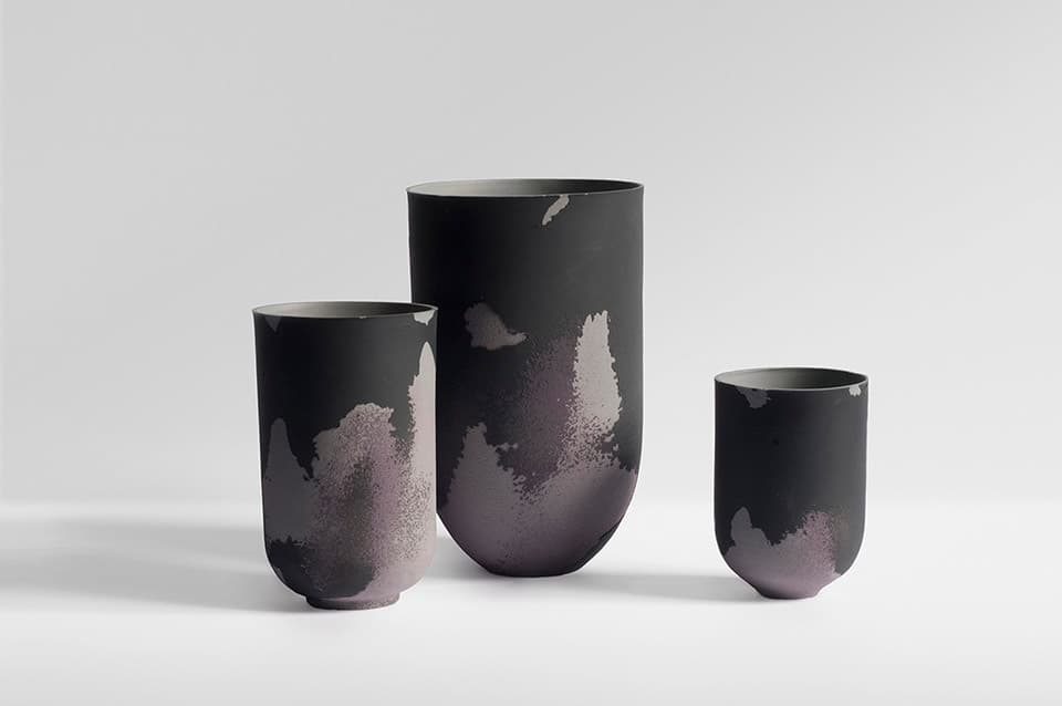 Three vases from Marie Liebhardt’s Flaws porcelain collection, with irregular pale patches across dark surfaces