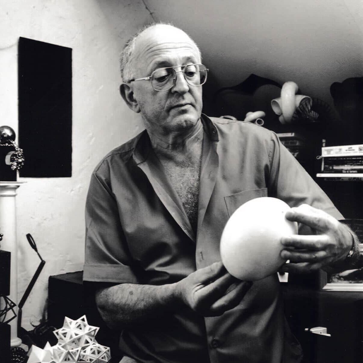 Serge Mouille in his studio holding a rounded form, as reproduced by the official history site.