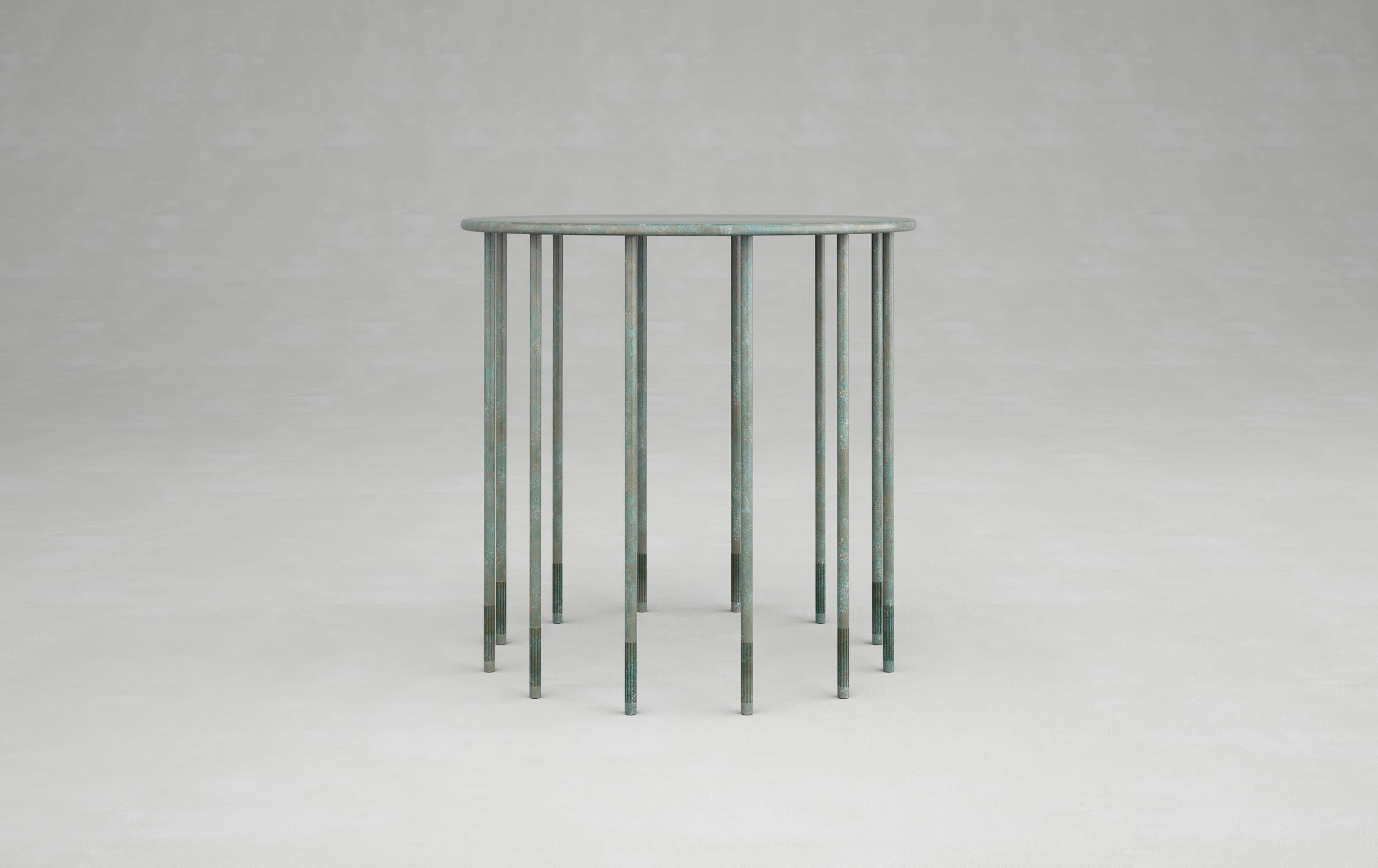 Tall circular blue-green table with numerous slender legs against a grey background.