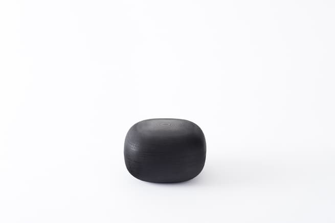 A dark rounded lacquered-paper container by Nendo
