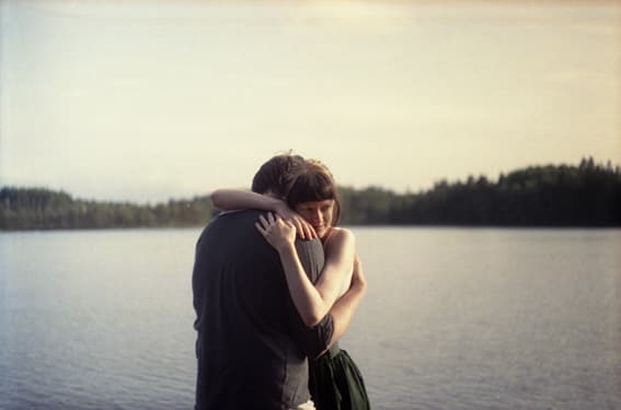 Two people embracing beside a lake.