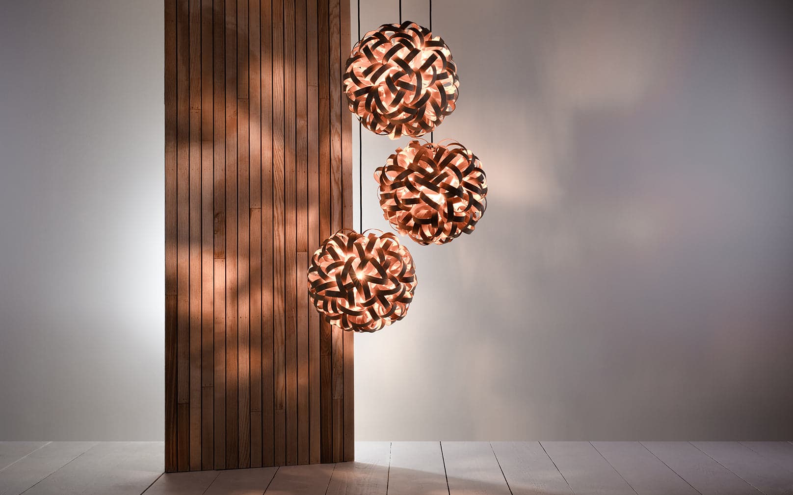 No.1 Pendant Cluster by Tom Raffield in oak, shown as three illuminated wooden pendants.