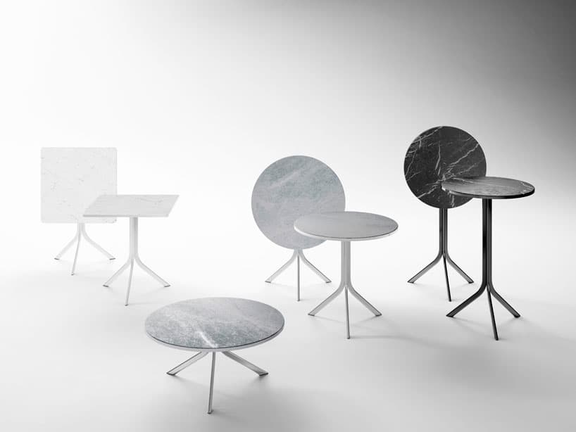 A group of Retegui Bistro tables with white, gray and dark veined marble tops and slender metal bases.