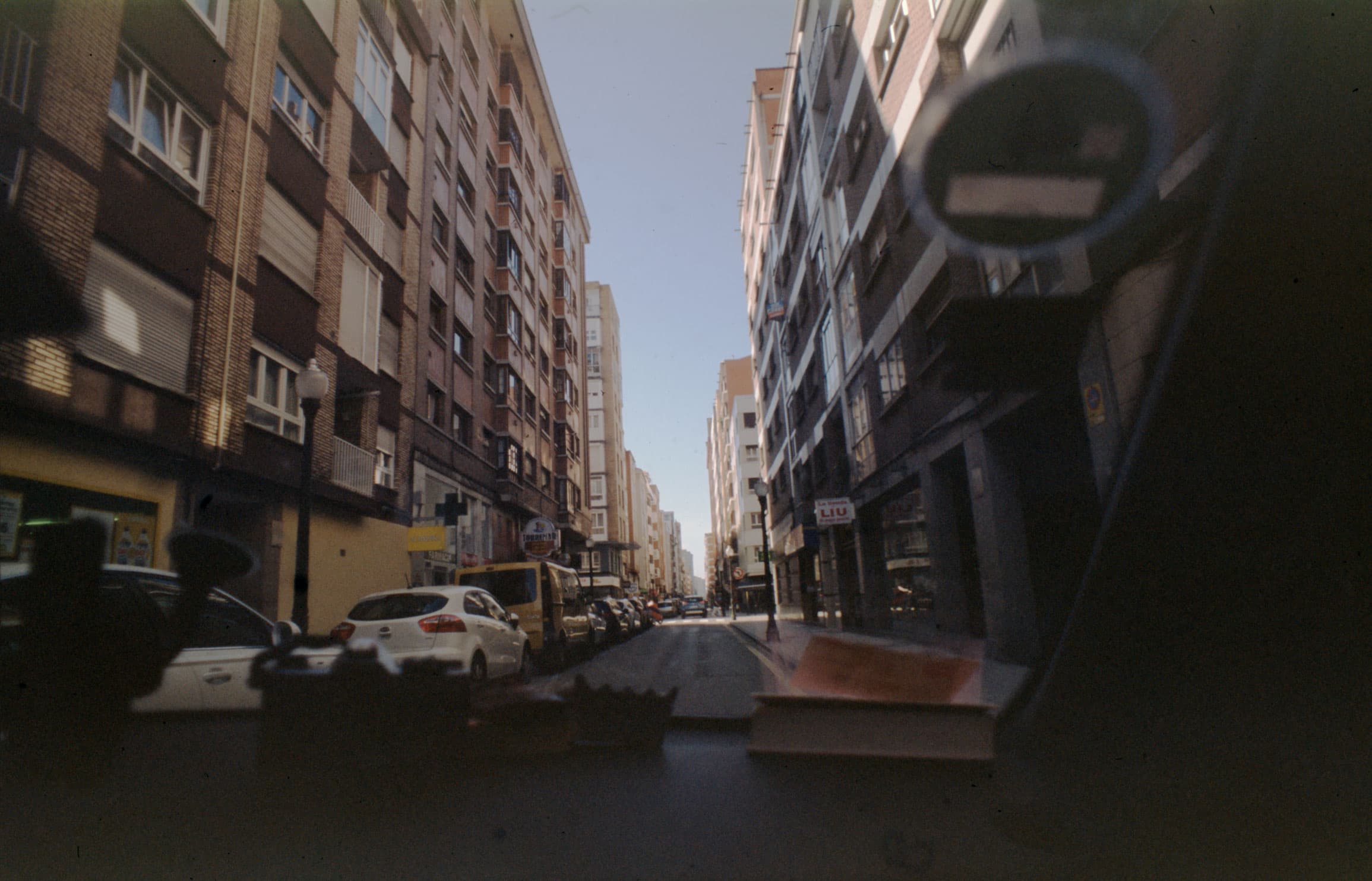 An urban street seen through a vehicle windscreen.