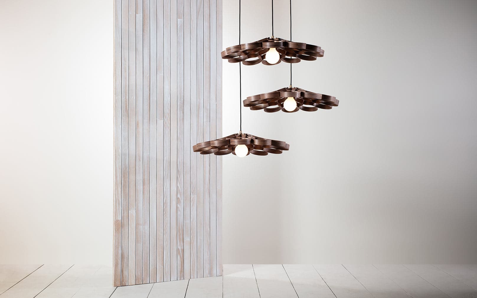 Arame Pendant Small Cluster by Tom Raffield in walnut, shown as three illuminated wooden pendants.