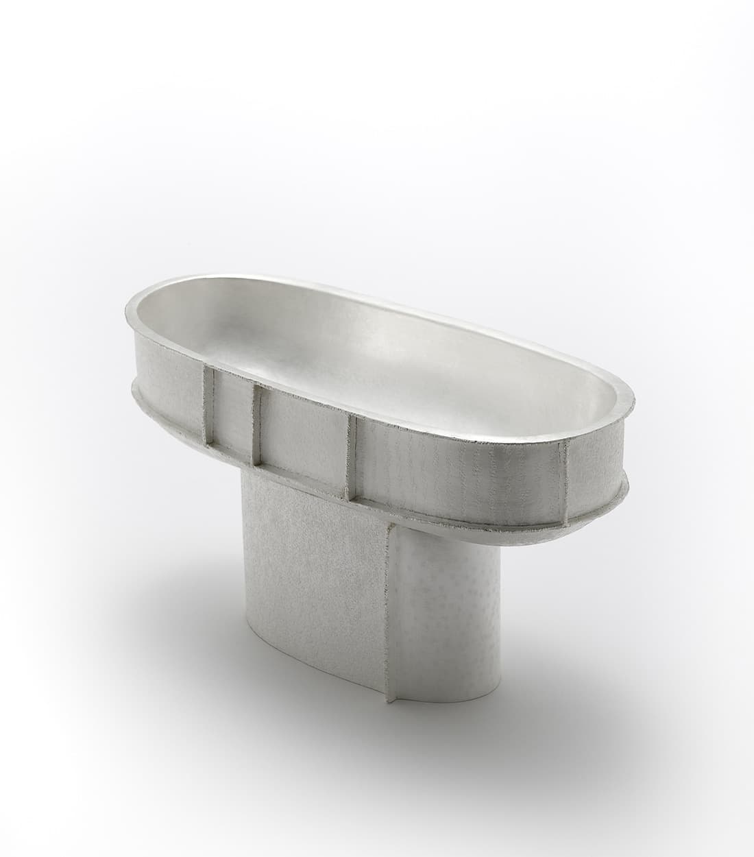 Silver-coloured elongated metal vessel with patterned sides and prominent welded joins, by Seung Hyun Lee.