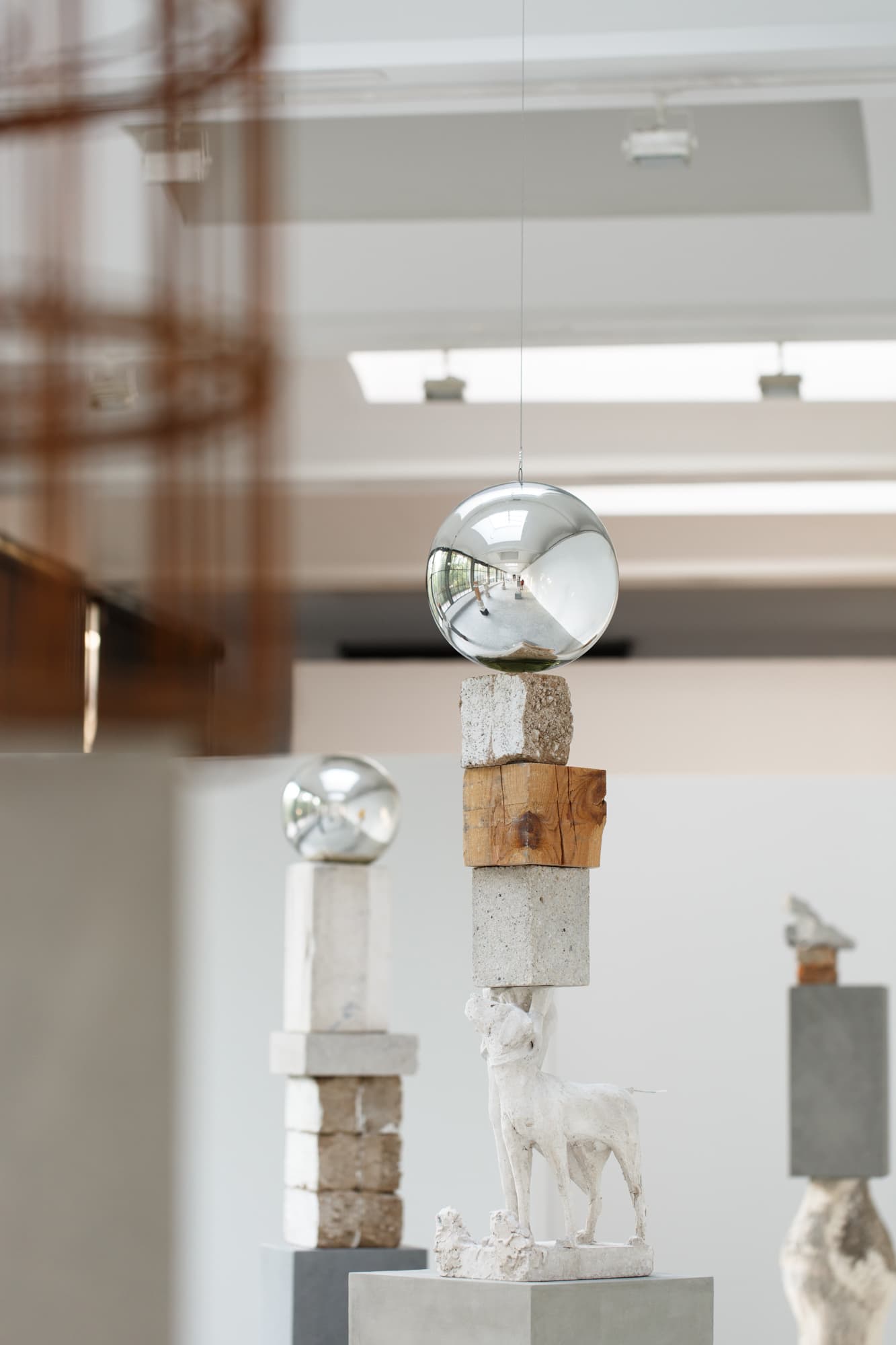 Reflective spheres and mixed-material sculptural columns in Jose Dávila’s Not All Those Who Wander Are Lost installation