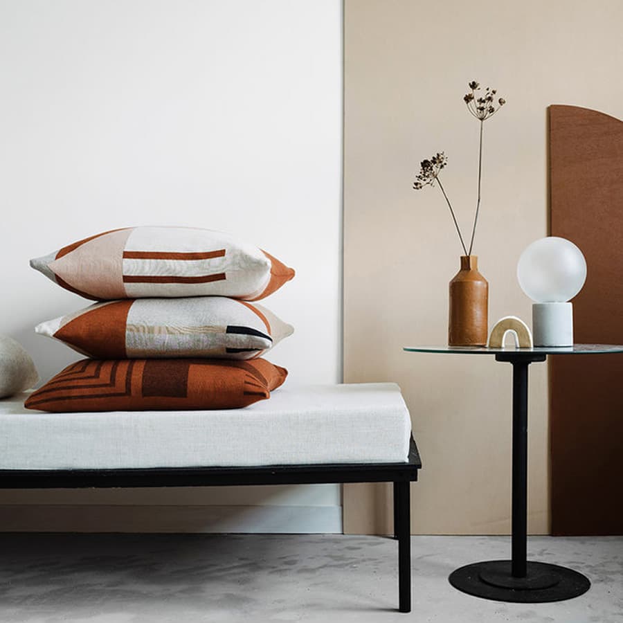 Three patterned cushions with terracotta line motifs in an interior