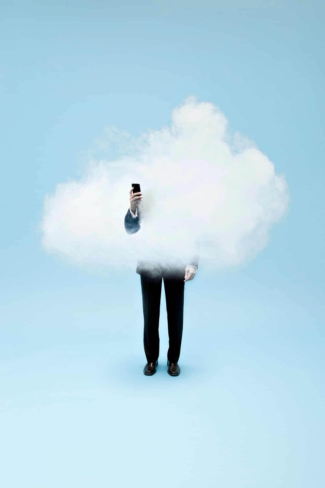 A person in a business suit holds a phone while a white cloud obscures their head and torso against a pale blue background.