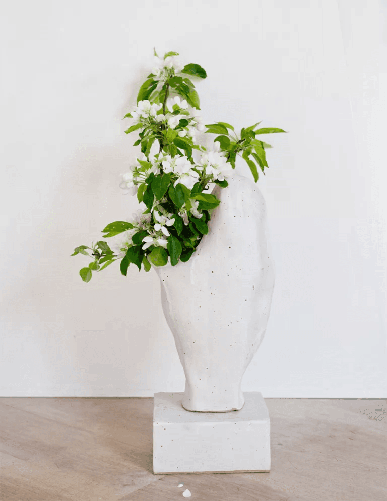 A sculptural ceramic vase by Noe Kuremoto with flowering branches.