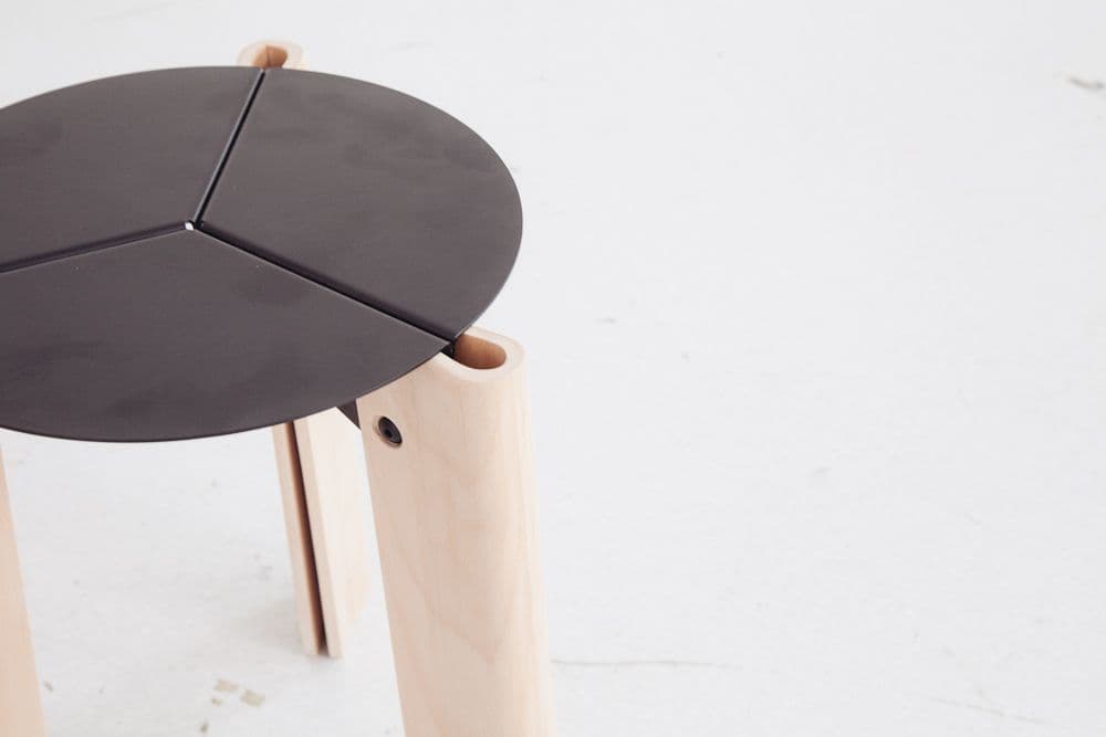 Detail of the Profil stool by Wojtek Tomaszewski, with a three-part metal seat and bent-plywood legs.