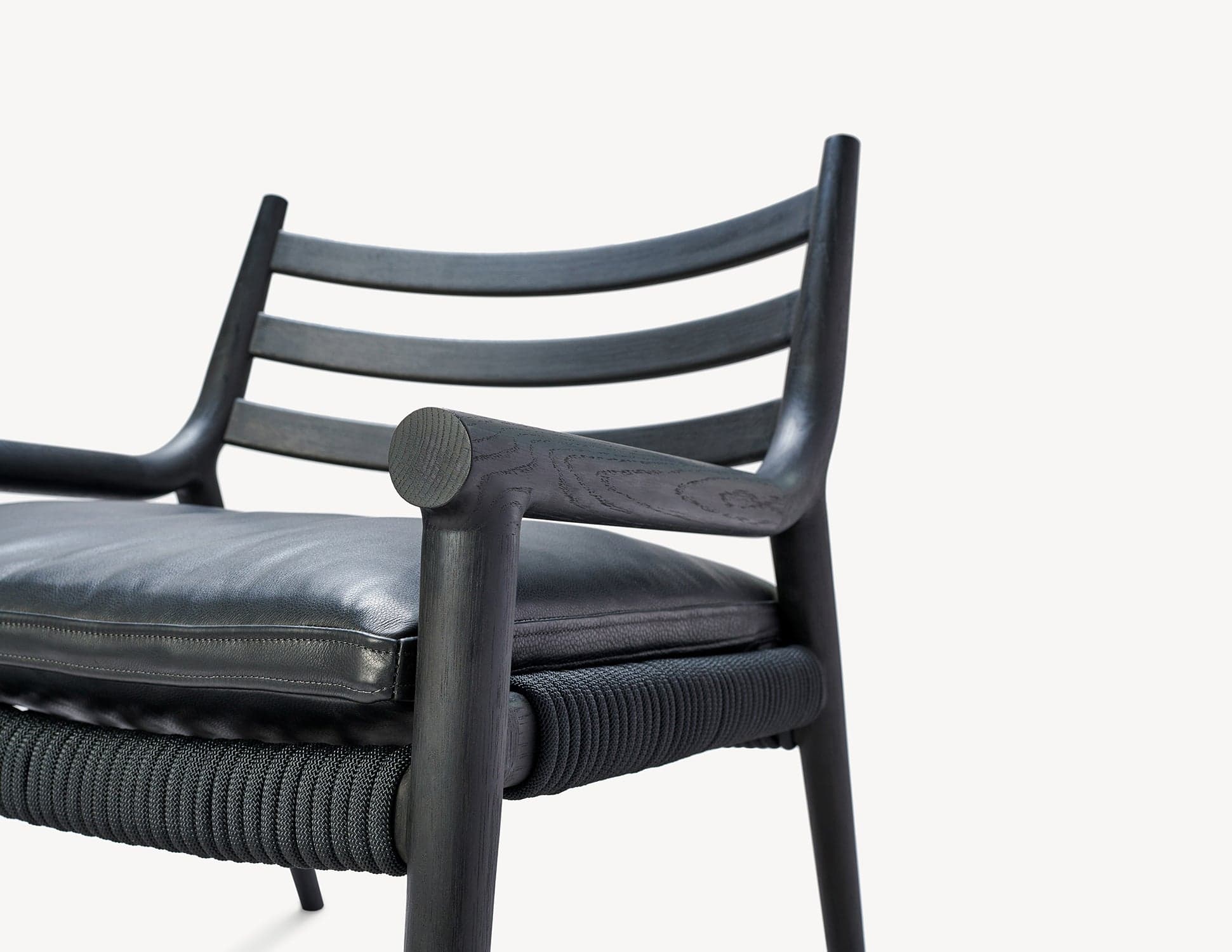 Black-finished Parkside Lounge detail, showing wooden joinery, a leather cushion and woven seat.