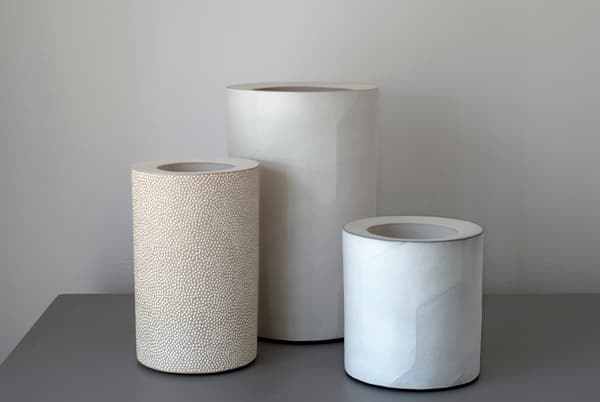 Three cylindrical vessels by Ann Jansson, including a left cylinder with a dotted surface.